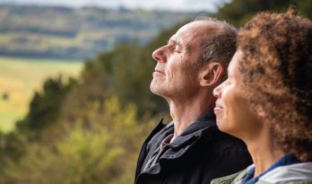 A couple with their eyes closed in a peaceful landscape