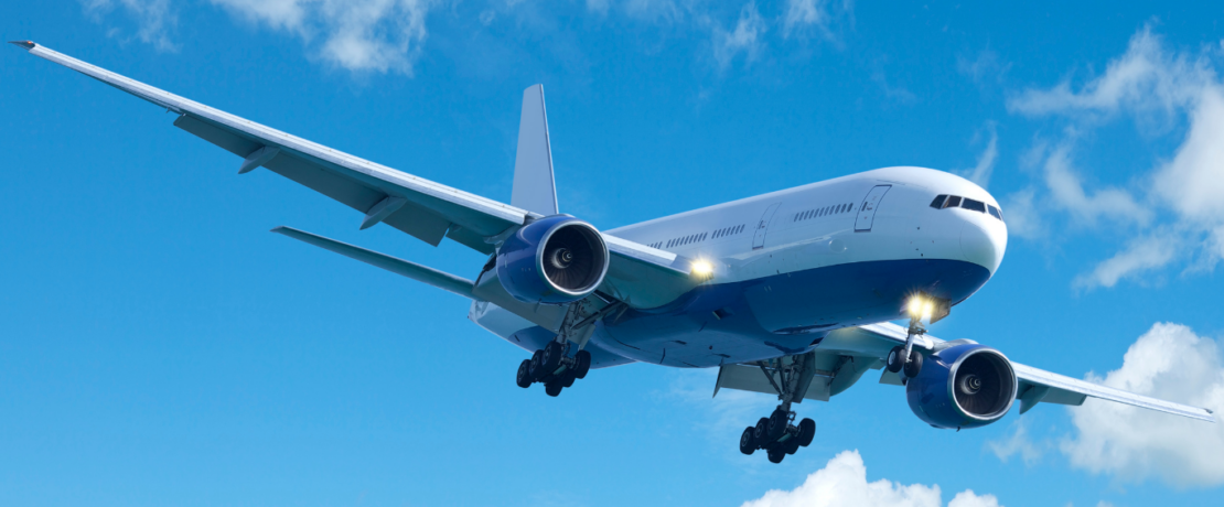 Image of an airplane in flght against a blue sky with wispy clouds