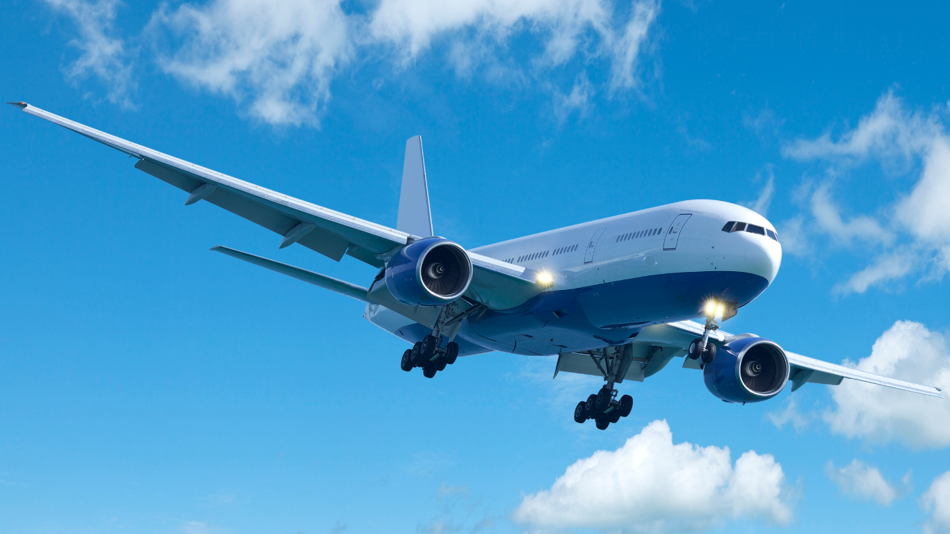 Image of an airplane in flght against a blue sky with wispy clouds