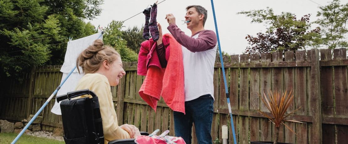 A man and young woman hanging out washing on a washing line