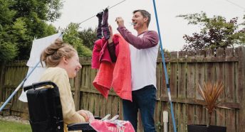 A man and young woman hanging out washing on a washing line