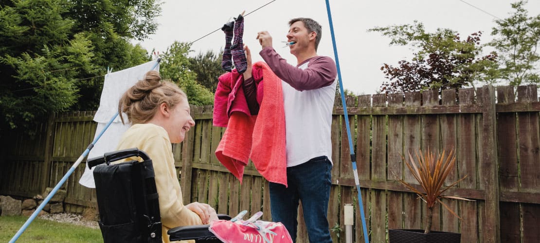 A man and young woman hanging out washing on a washing line