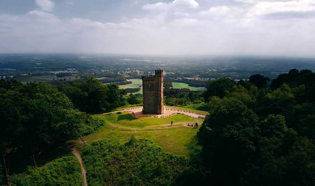 A short tower at the top of a hill with countryside views beyond