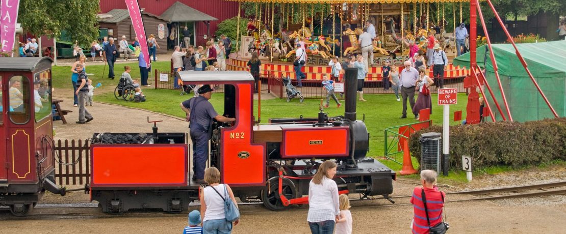 A busy play area with a carousel and miniature railway in the foreground