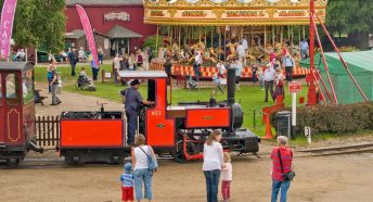 A busy play area with a carousel and miniature railway in the foreground