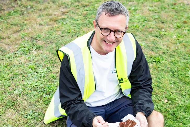 A CPRE volunteer in high vis top sits and eats cake