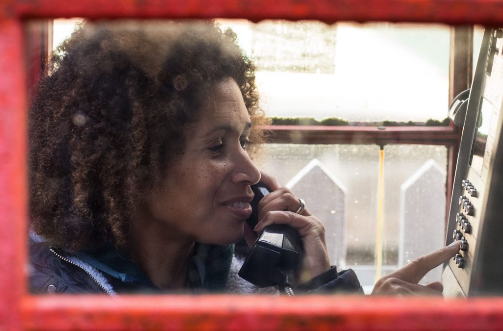 A lady in a traditional red phone box dials a number