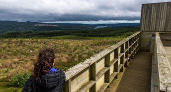 A woman stands outside Kielder Observatory looking over Kielder Water