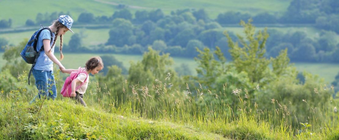 Two young girls walking on a hill