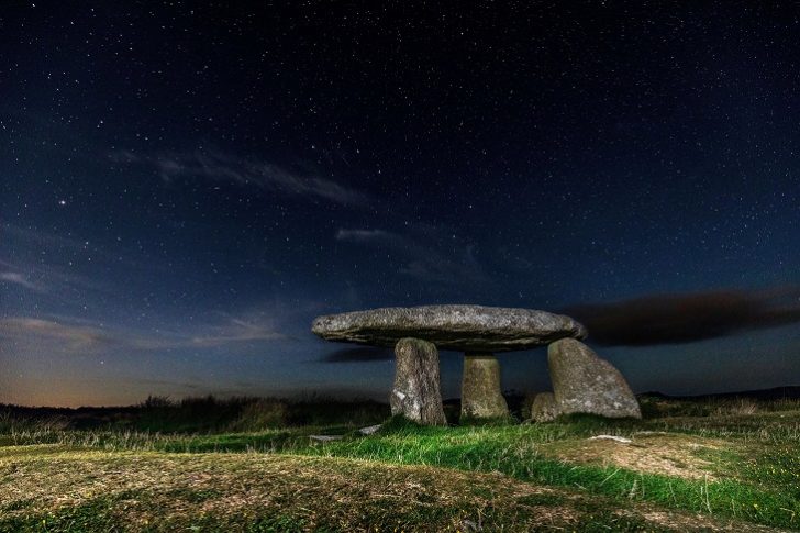 Ancient granite burial chamber stones at night against starry sky