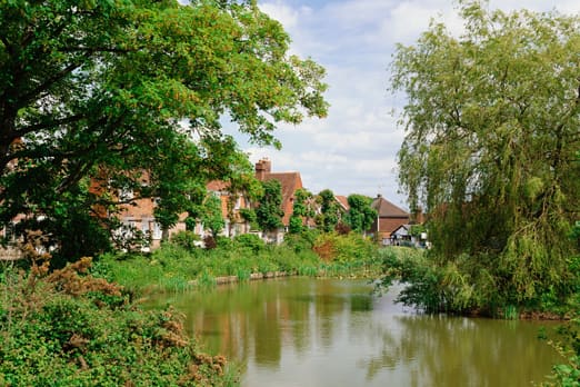 A peaceful view of a small river bending around a corner with houses on one bank