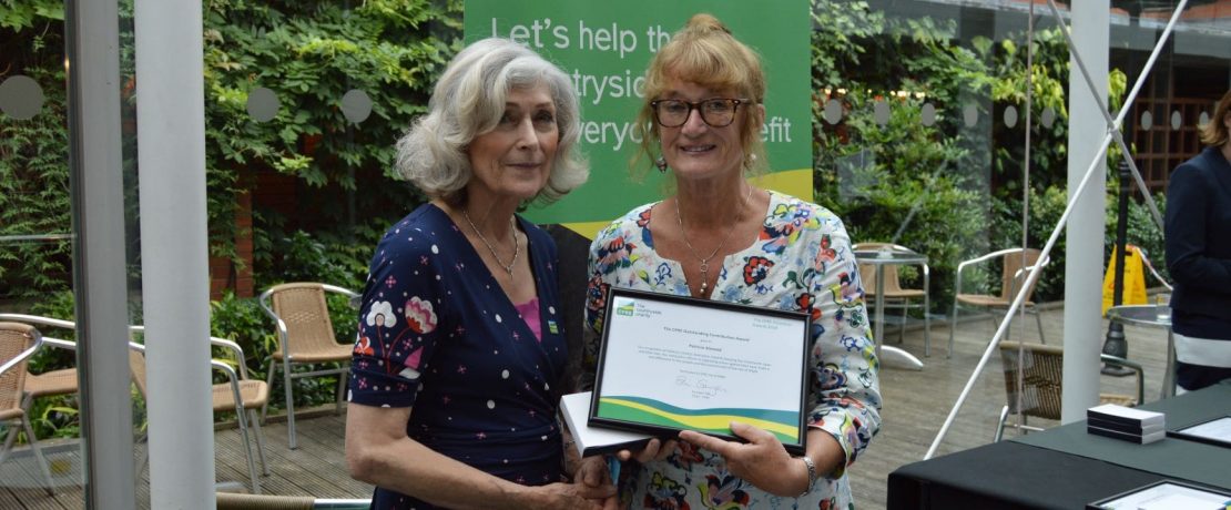 Two women shake hands as one is handed a framed certificate