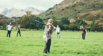 People playing rounders with large hills behind