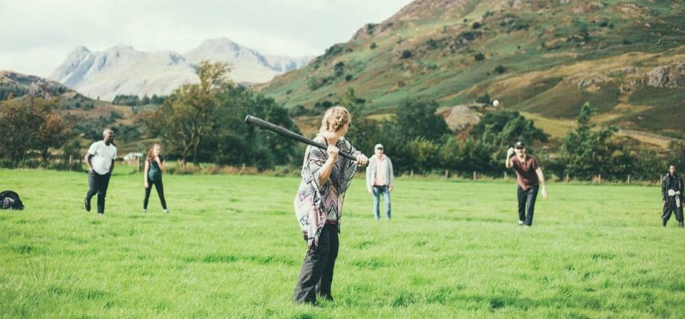 People playing rounders with large hills behind