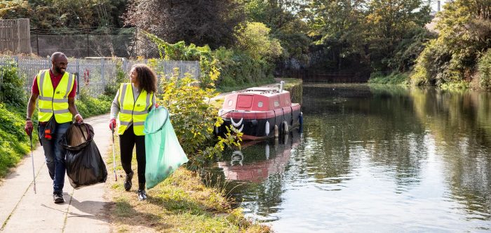 A man and woman walking as they litter pick beside a canal