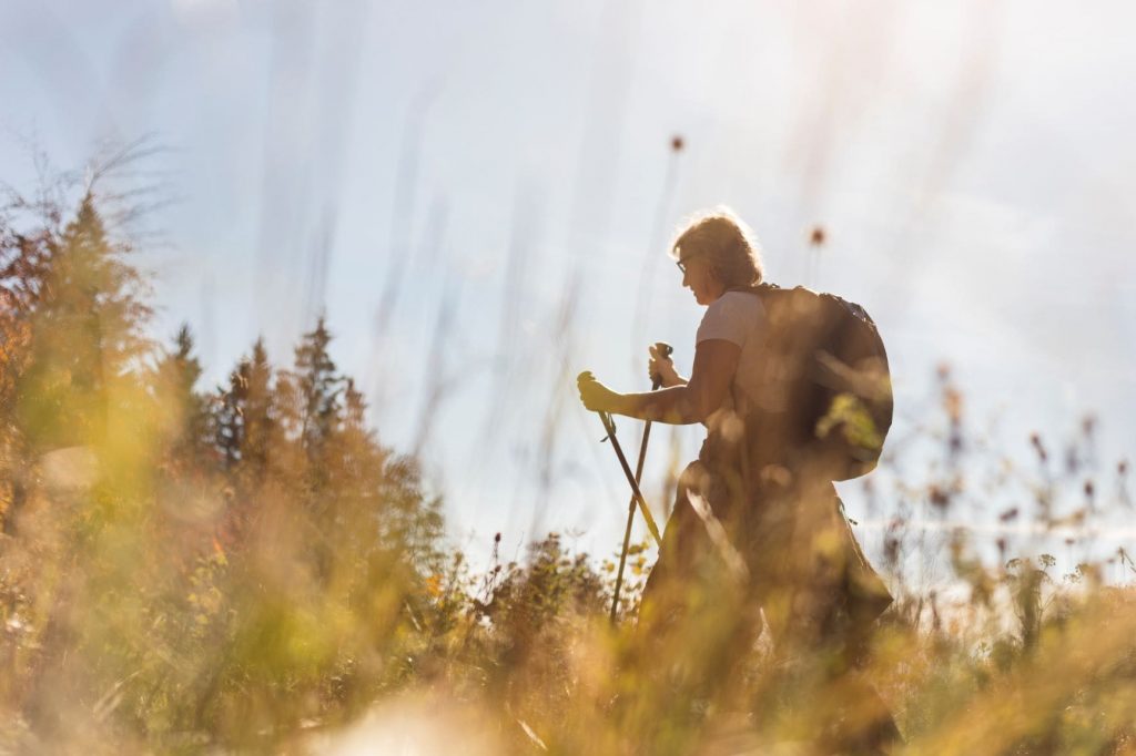 A woman hiking through a sunny field