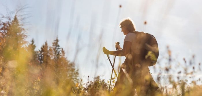 A woman hiking through a sunny field