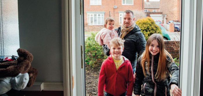 Family walking through door of house