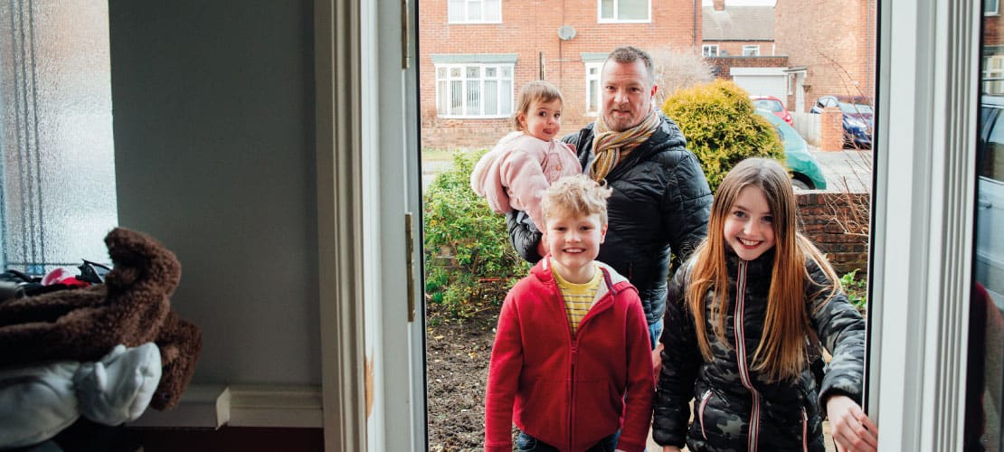 Family walking through door of house