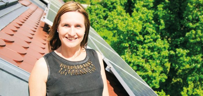 Woman in front of rooftop solar panels