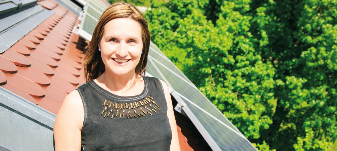 Woman in front of rooftop solar panels