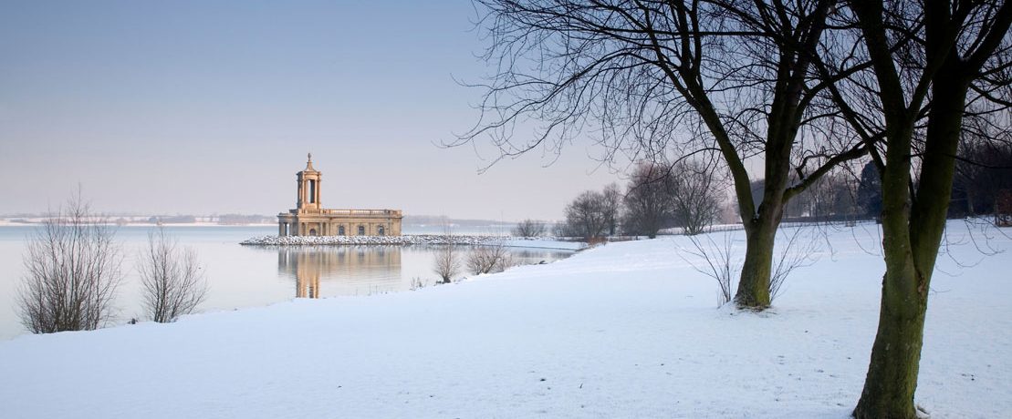 A building on the edge of a snowy waterfront in winter sunlight