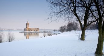 A building on the edge of a snowy waterfront in winter sunlight