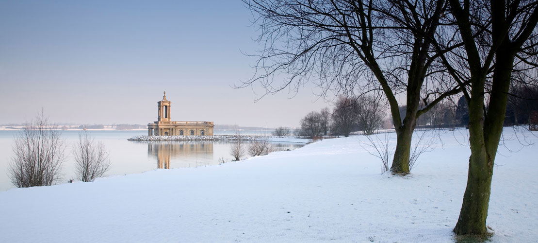 A building on the edge of a snowy waterfront in winter sunlight