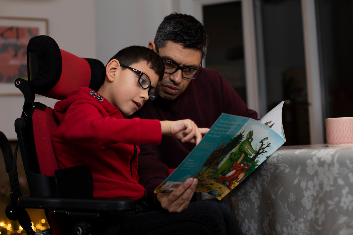 Man and boy reading a picture book inside a home at a table