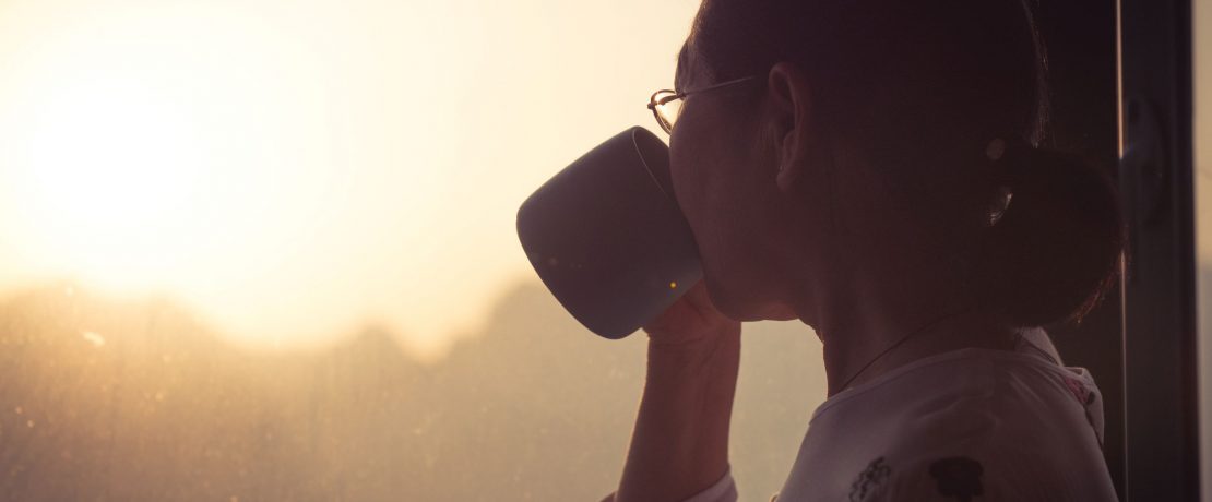 Woman drinking tea while admiring view from window
