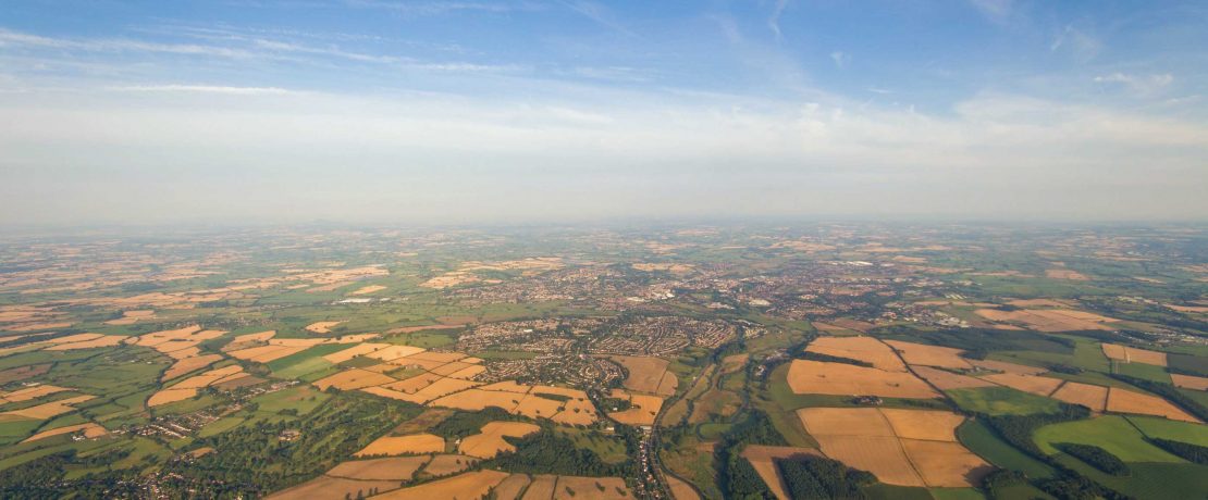 A view of a wide horizon with fields of crops and a cloudy sky