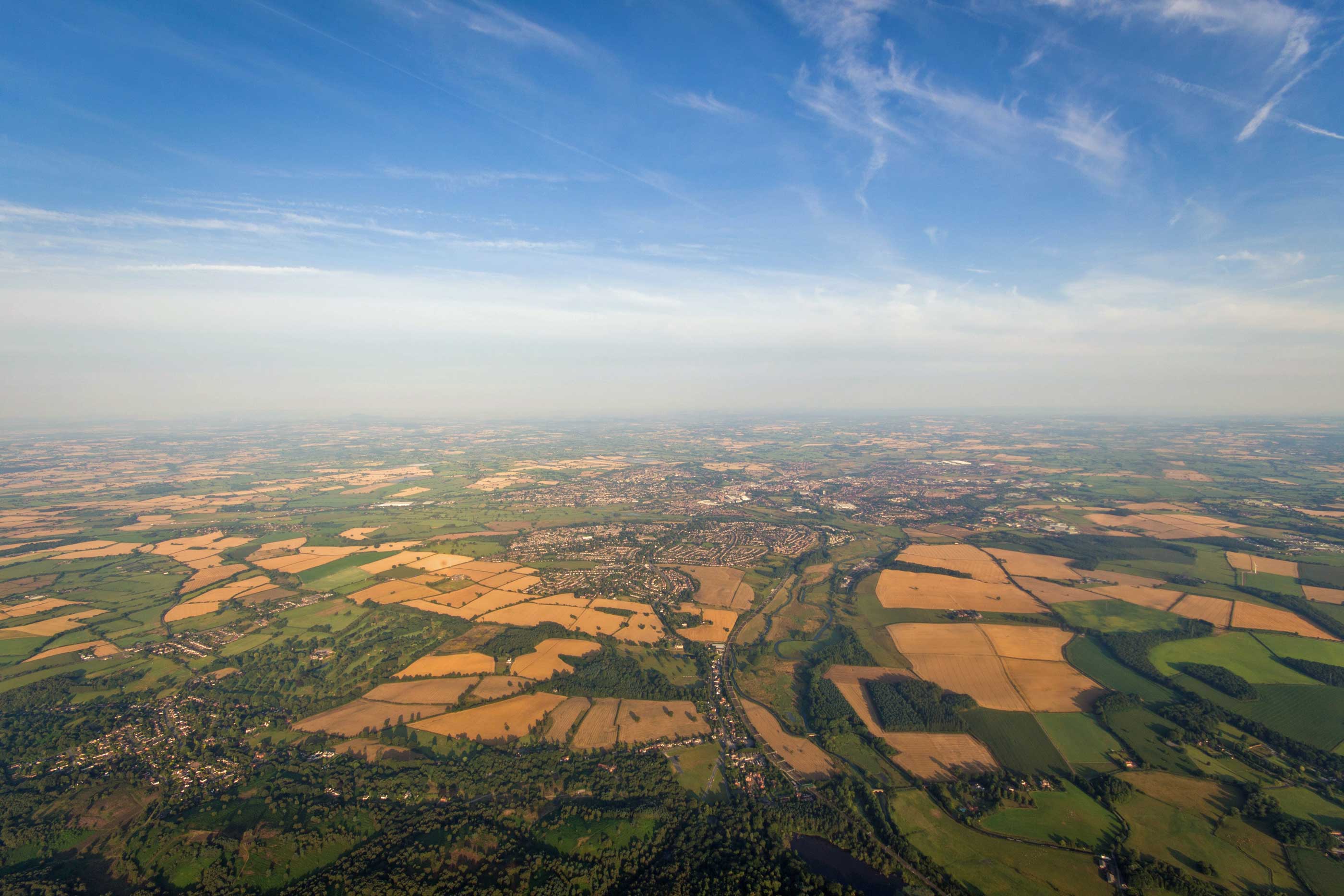 A view of a wide horizon with fields of crops and a cloudy sky