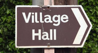 A brown village hall sign