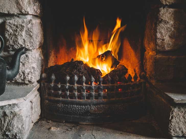 Blocks of dark peat burn a lively fire in a domestic stone fireplace