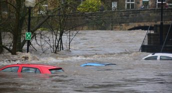 A flooded street with water almost covering car rooftops