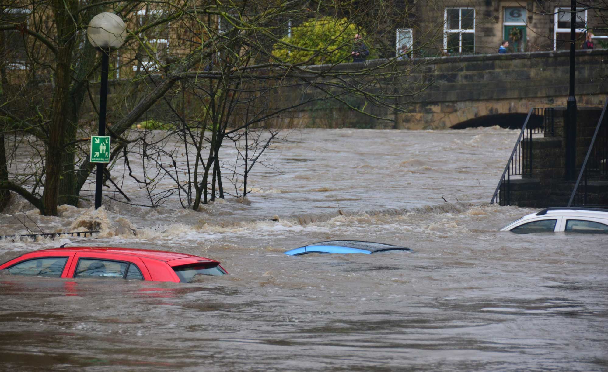 A flooded street with water almost covering car rooftops