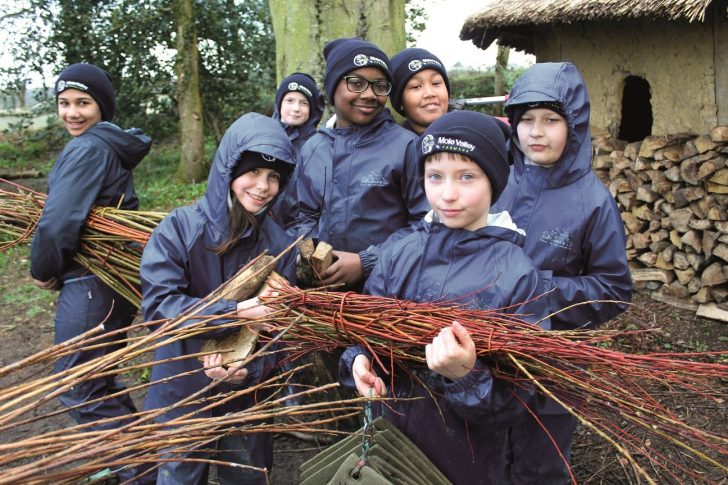 Group of schoolchildren carrying twigs