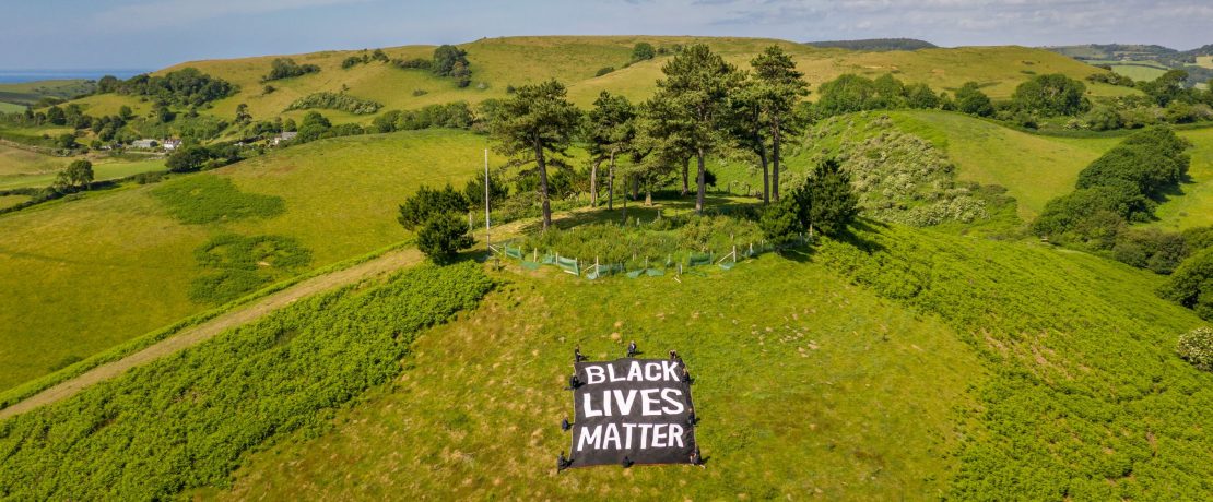 Black Lives Matter banner and people kneeling in Dorset landscape