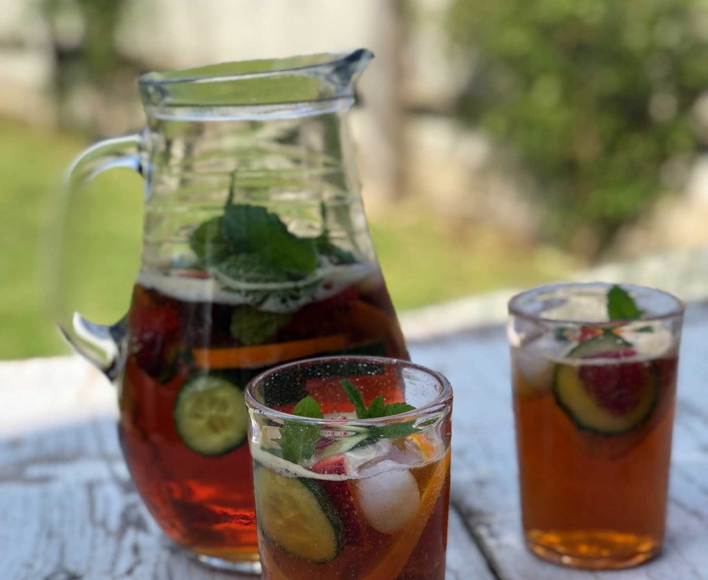 Two glasses and a jug of Pimms in a garden