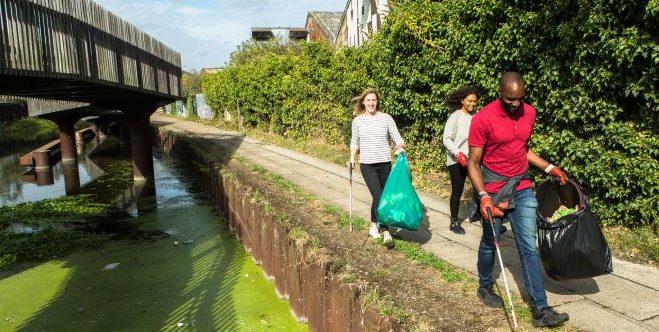 Three people litter picking by a canal