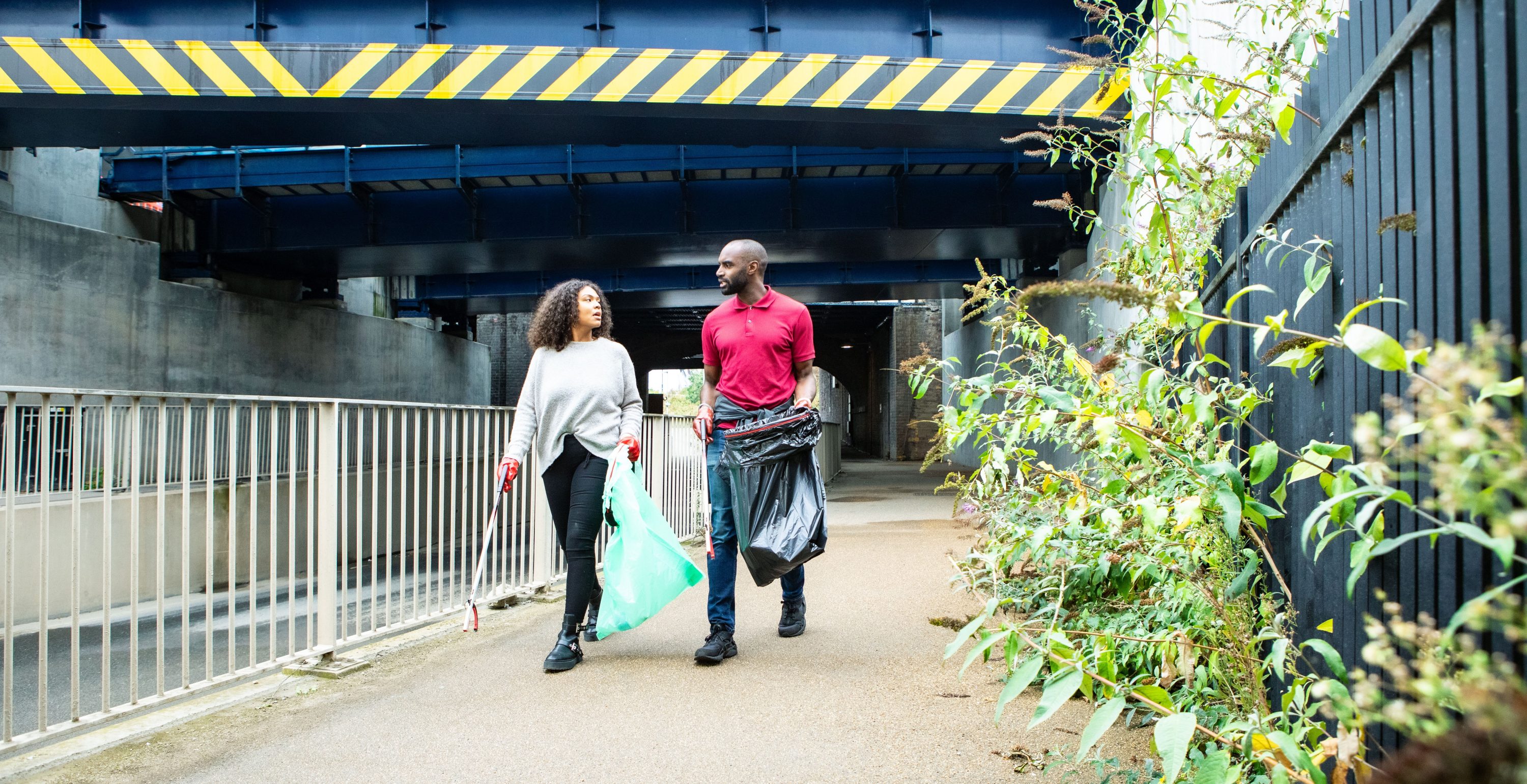 Man and woman walking under bridge with litter picking equipment