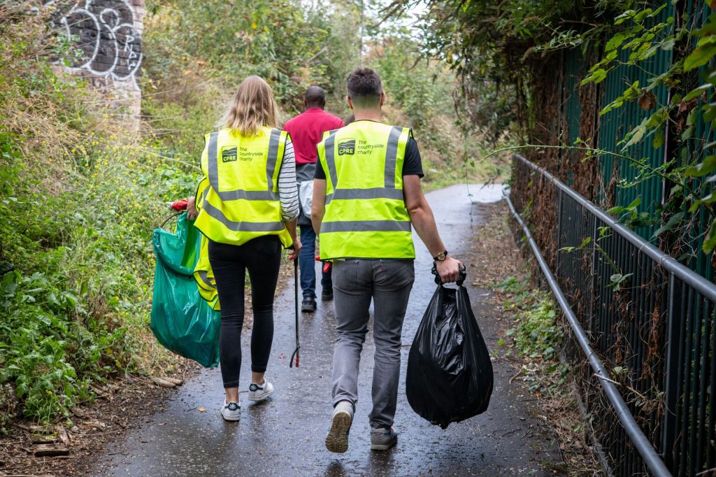 Volunteers on litter pick walking away from camera with sacks of litter