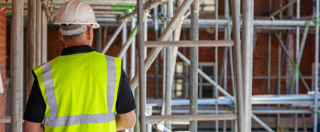 A builder in a high visibility vest on a building site