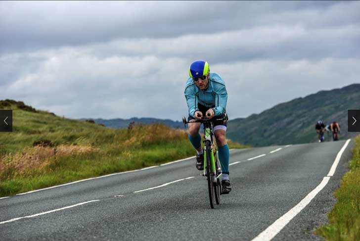 Man leaning over bike and cycling fast on a road