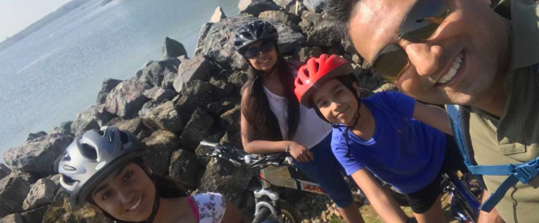 A father and three children on bikes beside the sea