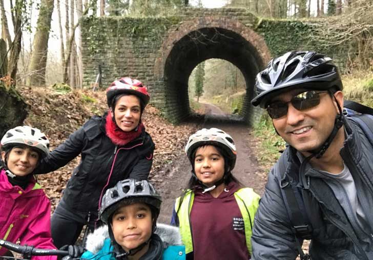 A family pose on bikes on a wooded track