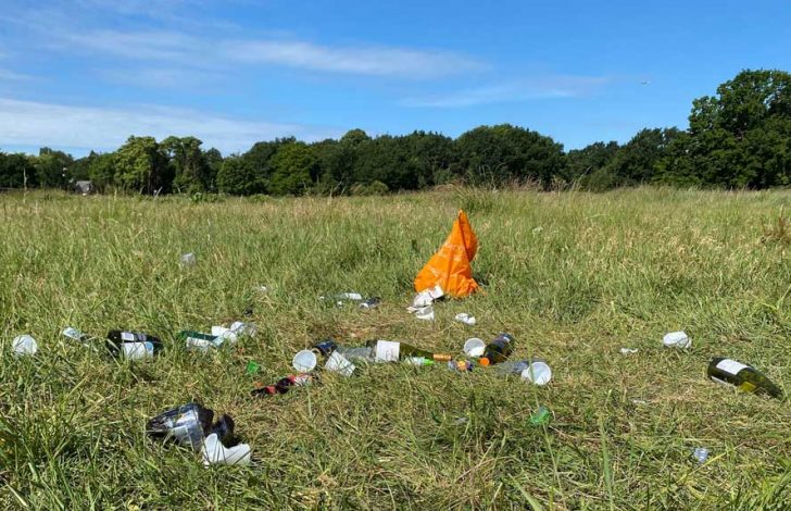 Bottles, a plastic bag and plastic cups discarded in a grassy area