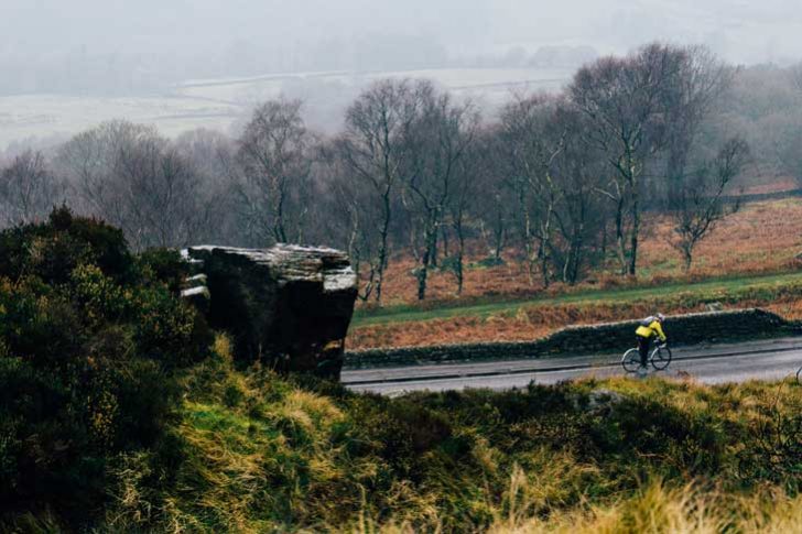 A cyclist on a dramatic wooded high pass