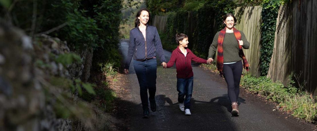 Two women walk on a lane holding a boy's hand