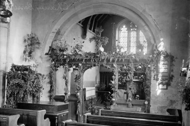 A black and white shot of a church interior with floral decoration